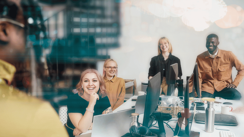Personer i ett arbetsteam i ett konferensrum som ler och lyssnar till person som pratar