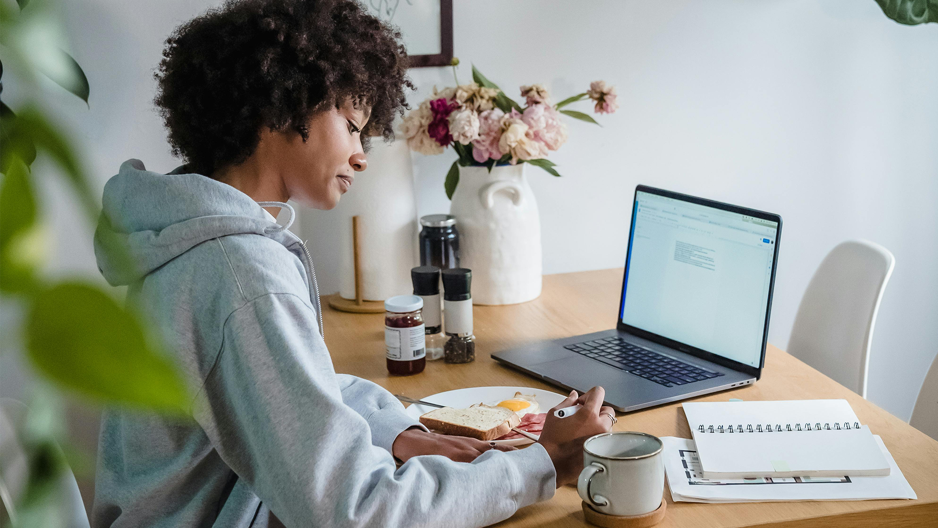En jvinna som sitter vid ett körsbord med laptop framför sig och skriver