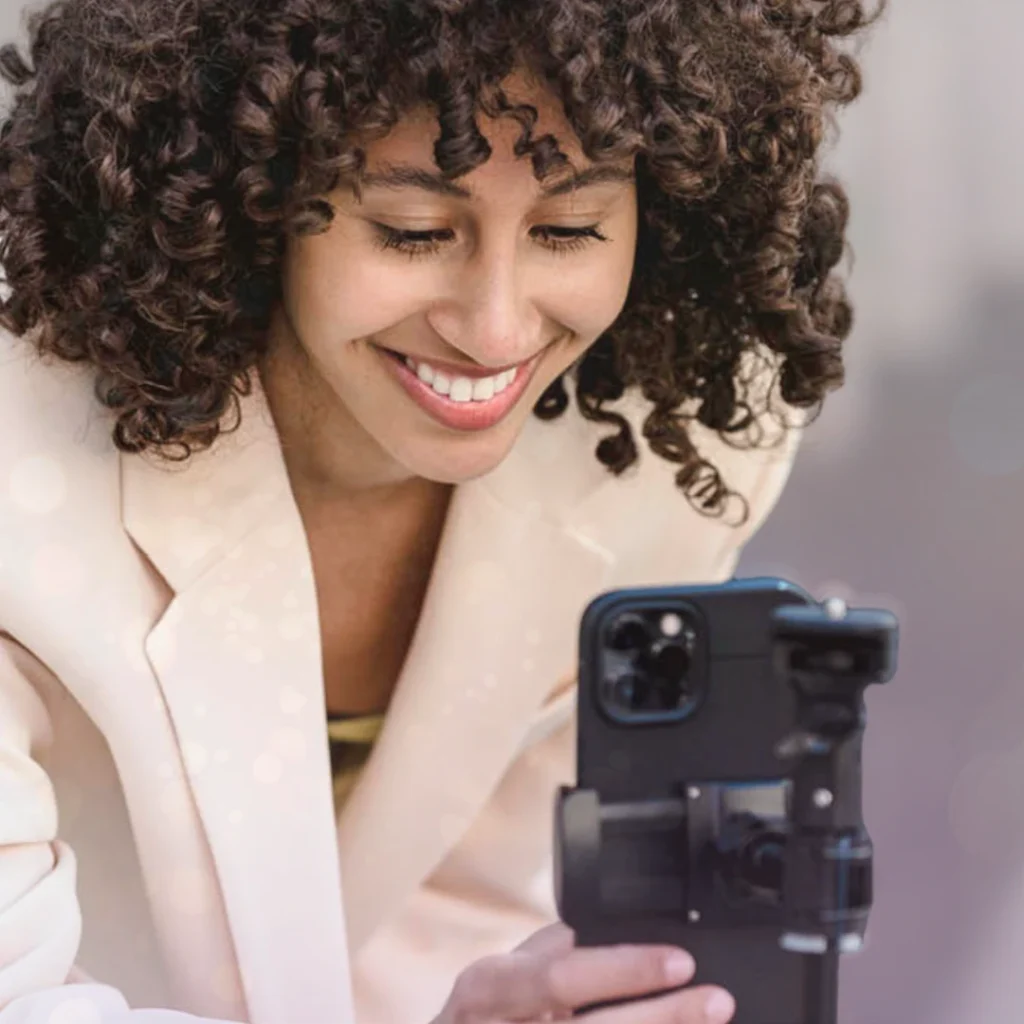 En tjej som arbetar med influncer marketing och står bakom en kamera för att justera inställningarna