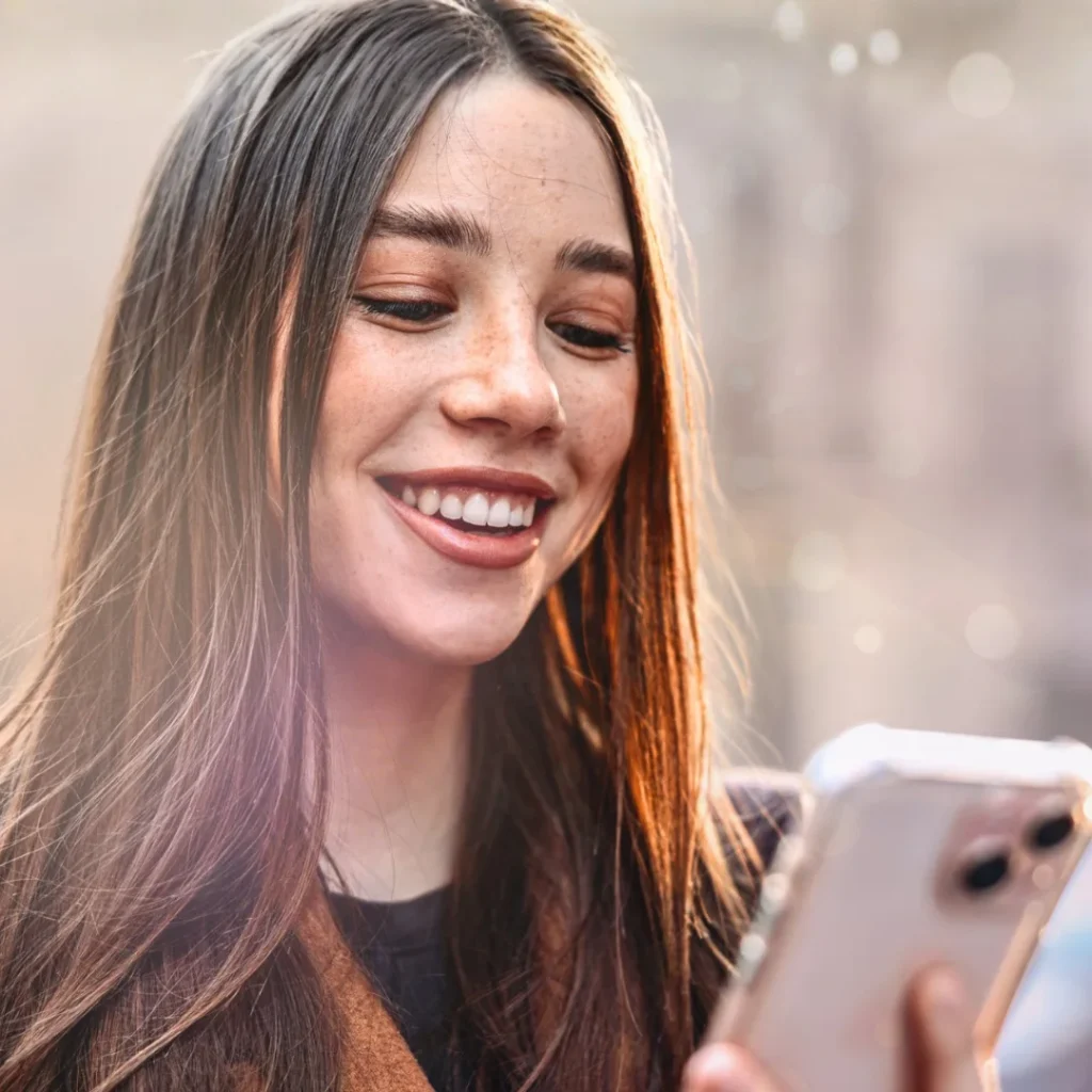 Kvinna som står utomhus och tittar ner i telefonen från sälj & marknadshögskolans Upskill & Reskill coachingprogrammet